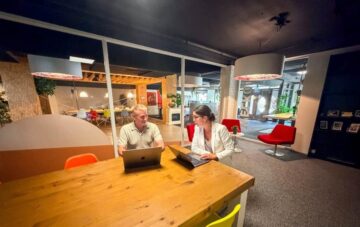 Ondernemer krijgt uitleg over de AI-verordening voor zijn website tijdens een overleg met laptops in het kenniscentrum van Kwaaijongens